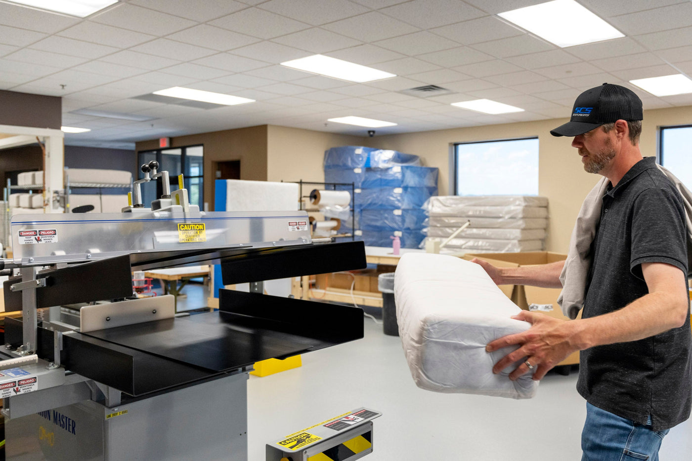 Person working with a cushion stuffing machine in a clean warehouse setting
